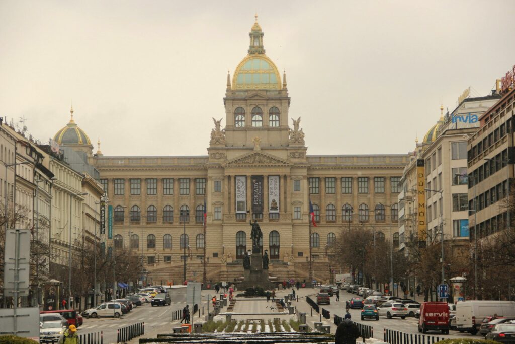 Street view of the National Museum in Prague on an overcast day, capturing urban life.